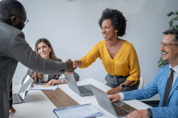 people in a meeting in the office and two people are shaking hands